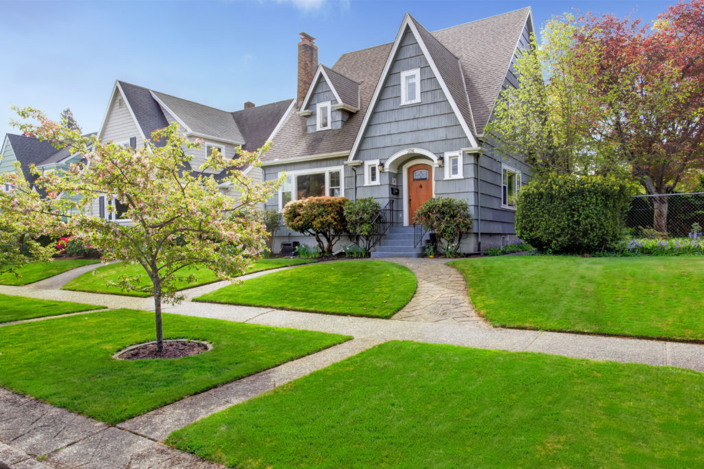 Blue house with lush green grass in front yard