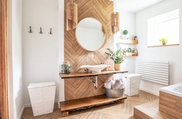 White sink on wood counter with a round mirror hanging above it. Bathroom interior.