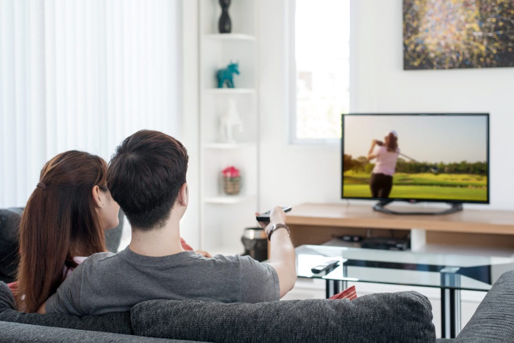 Couple watching golf on tv in their homeliving room