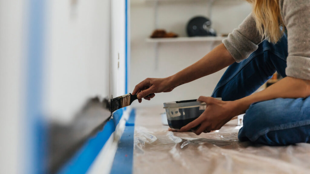 Woman sitting painting wall at home