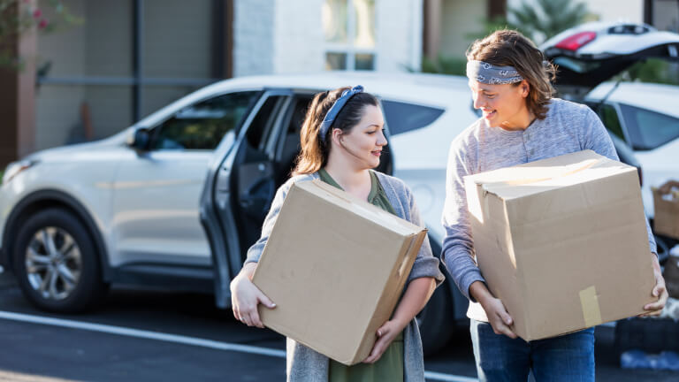 Young couple moving, unloading car in parking lot