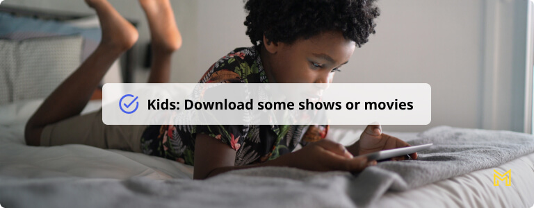 Boy lying in bed playing games on digital tablet at home