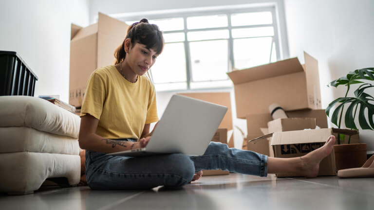 Young woman using laptop at new house