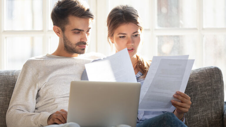 Focused couple sitting on couch reading received formal letter