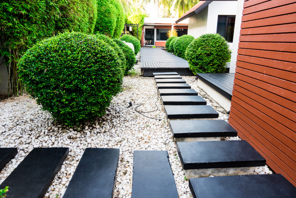 Lawn walkway landscaped with large black stones and white pebbles